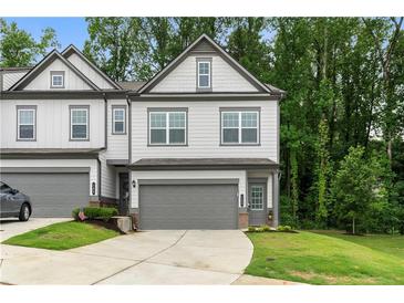 Charming gray two-story townhouse with a one car garage, manicured lawn and a concrete driveway at 153 Witter Way, Woodstock, GA 30188