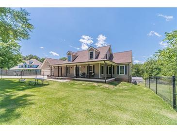 Charming home featuring a long porch, fenced yard, dormer windows, and lush green lawn and professional landscaping at 3040 Sandy Creek Ct, Loganville, GA 30052