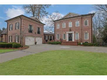 Elegant brick home featuring a circular driveway, manicured lawn, and a detached two-car garage at 4084 Peachtree Dunwoody Rd, Atlanta, GA 30342