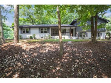 Charming two-story home featuring a mix of painted brick and siding, complemented by mature trees and manicured landscaping at 2445 Kings Point Dr, Dunwoody, GA 30338