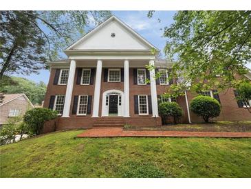 Stately brick home featuring white columns, black shutters, and a manicured front lawn on a lush, green lot at 1595 Bakers Glen Dr, Atlanta, GA 30350