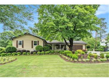 Charming home featuring a lush front yard with manicured landscaping and mature trees, creating inviting curb appeal at 733 Huntington Se Pl, Marietta, GA 30067