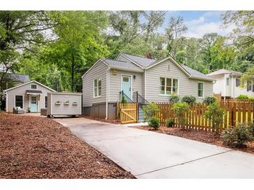 Charming home with light gray siding, a bright blue front door, a fenced front yard, and a separate detached guest house at 1583 Braeburn Se Dr, Atlanta, GA 30316