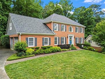 Beautiful two-story brick home with manicured lawn and lovely landscaping with a blue front door at 4792 Fairville Ct, Marietta, GA 30062