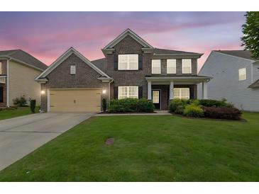 Charming two-story brick home with a well-manicured lawn and welcoming front porch at 7190 Tributary Ct, Cumming, GA 30040