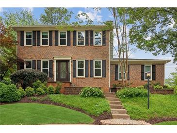 Charming two-story brick home with black shutters and a beautifully landscaped front yard at 9800 Woodfall Dr, Roswell, GA 30076