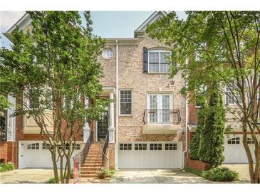 Charming brick townhome featuring a front porch, balcony, and attached two-car garage at 1040 Emory Parc Pl, Decatur, GA 30033