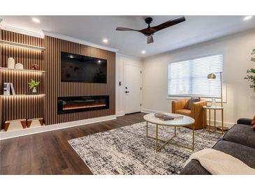 Stylish living room features a modern fireplace, sleek ceiling fan, and decorative wood accent wall with built-in shelving at 4282 Roswell Ne Rd # G1, Atlanta, GA 30342