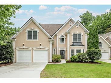 Charming home with a well-manicured lawn, two-car garage, and neutral stucco facade at 1921 Northbrooke Ln, Dunwoody, GA 30338