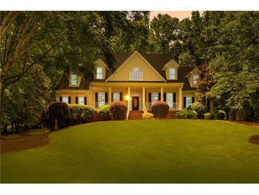 Traditional home with manicured lawn, mature trees, and inviting covered front porch at 220 Broadmoor Dr, Fayetteville, GA 30215