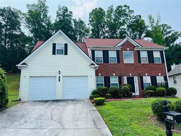 Charming two-story home with a brick and siding exterior, attached two-car garage, and manicured lawn at 5123 Upper Elm St, Atlanta, GA 30349