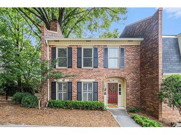 Charming brick townhome with black shutters, a red door, and lush landscaping at 6 Stratford Hall Ne Pl, Atlanta, GA 30342