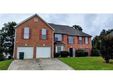Traditional brick home featuring a two-car garage, shutters, and well-maintained landscaping at 4373 Abram Dr, Conley, GA 30288