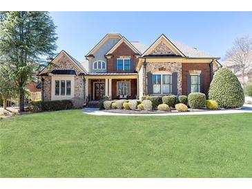 Charming two-story home with brick and stone accents, manicured lawn, and mature trees at 5352 Lacosta Ln, Alpharetta, GA 30022