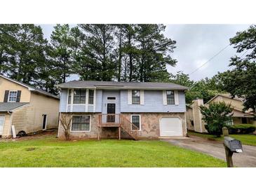 Split-level home boasts stone accents, a front porch, attached garage, and a well-manicured front lawn at 2168 Sara Ashley Way, Lithonia, GA 30058