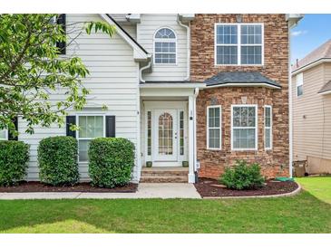Charming entryway with a white front door, stone accents, and well-maintained landscaping at 910 Pebble Creek Trl, Suwanee, GA 30024