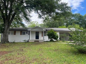 Ranch-style home featuring a white brick exterior, covered entrance, and lush greenery at 1066 Cleavemark Dr, Clarkston, GA 30021