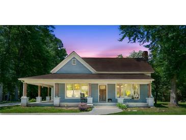 Charming blue home with a covered front porch and a beautiful dusk sky in the background at 1382 6Th Ave, Auburn, GA 30011