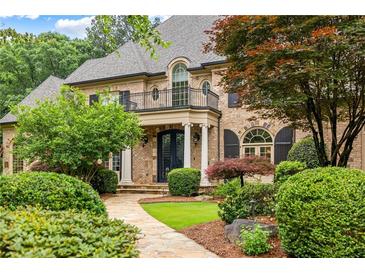 Beautiful brick home featuring a stone walkway, manicured landscaping, a second story balcony, and an iron front door at 816 Blackfoot Trl, Suwanee, GA 30024