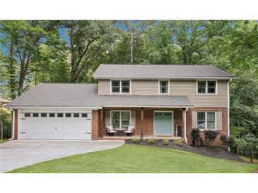 Charming two-story home featuring a brick and siding exterior, a two-car garage, and a welcoming front porch at 4733 Eidson Road, Dunwoody, GA 30360