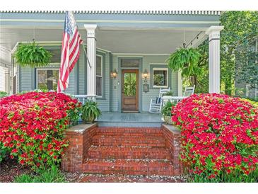 Inviting front porch with vibrant flowers, rocking chairs, and an American flag display at 513 Saint Charles Ne Ave, Atlanta, GA 30308