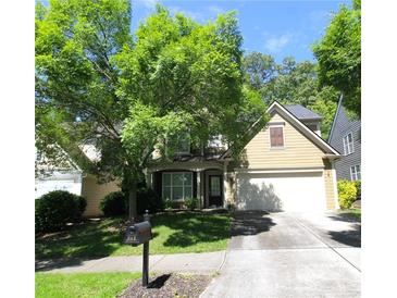 Charming home with a well-manicured lawn, mature trees, and a two-car garage on a sunny day at 942 Idlewood Dr, Canton, GA 30115