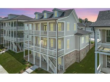View of three story home featuring double balconies and brick accents on the ground level at 1294 Six Sisters St, Dacula, GA 30019