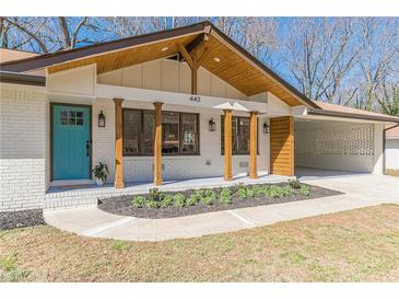 Charming brick home featuring a welcoming porch with wooden columns and a lovely turquoise front door at 442 Mountain Park Trl, Stone Mountain, GA 30087