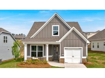 Charming single-Gathering home featuring vertical siding, an attached garage, and a cozy front porch sitting area at 71 Colonial Terrace, Villa Rica, GA 30180