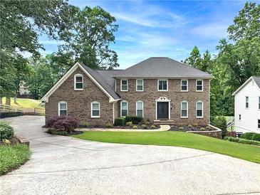 Stunning brick home featuring a meticulously landscaped yard and an extended driveway at 10300 Carleigh Ln, Roswell, GA 30076