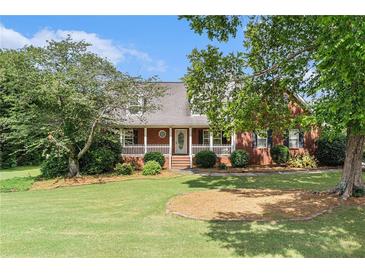 Charming brick home with a well-manicured lawn and inviting front porch with white picket fence detailing at 1112 Sutton Dr, Mcdonough, GA 30252