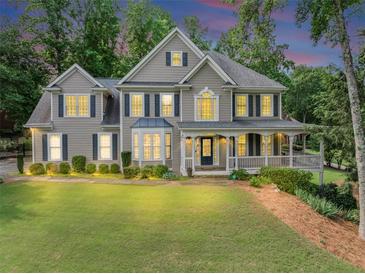 Charming two-story home features a spacious porch, manicured lawn and beautiful, mature trees at 1245 Smokehouse Trl, Cumming, GA 30041