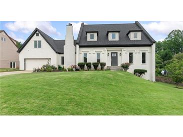 Charming home featuring a well-manicured lawn, black roof, white facade, and an attached garage at 1645 Oakfield Ln, Roswell, GA 30075