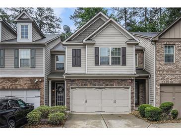 Charming townhome with a two-car garage, neutral siding, stone accents, and manicured landscaping at 2294 Spicy Pine Ln, Lawrenceville, GA 30044