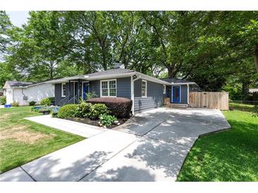 Charming home with gray siding, a blue front door, landscaped yard, and a concrete driveway at 957 Sharon Se Cir, Smyrna, GA 30080