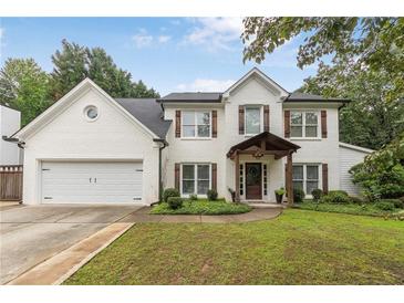 Charming two-story home featuring a lush front yard, white brick facade, and inviting entryway at 2205 Waters Ferry Dr, Lawrenceville, GA 30043