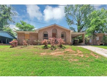 Charming brick home featuring a covered front porch and carport, complemented by a lush green lawn and mature trees at 5267 Sheppard Ln, Stone Mountain, GA 30083