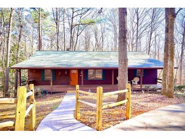 Charming wood cabin with a covered front porch surrounded by a tranquil wooded landscape at 3452 Monica Lane Southwest Sw Ln, Conyers, GA 30094