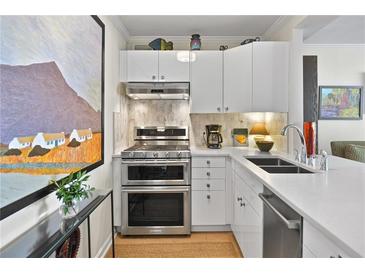 Modern kitchen with stainless steel appliances, sleek white cabinetry, and stone backsplash at 620 Peachtree Ne St # 1111, Atlanta, GA 30308
