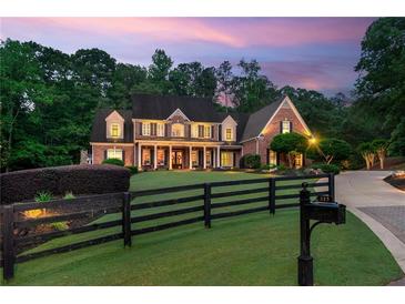 A brick two-story home has a manicured front yard with a black fence, plus a long driveway at dusk at 325 Edwards Brook Ln, Canton, GA 30115