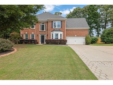 Charming two-story brick home with well-maintained lawn and mature trees, showcasing classic curb appeal at 285 Finsbury Park Ct, Suwanee, GA 30024