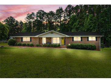 Charming brick home featuring a well-manicured lawn and front-facing shrubs at 8070 Johnson Rd, Palmetto, GA 30268