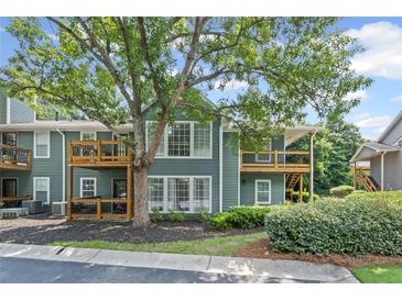 Inviting condominium with a wood balcony, surrounded by lush landscaping and mature trees at 202 Berkeley Woods Dr, Duluth, GA 30096