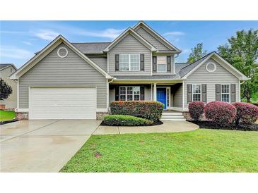 Beautiful two-story home featuring a manicured lawn, charming shutters and a blue front door at 327 Oakland Bay Ct, Loganville, GA 30052