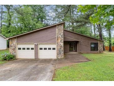 View of a single-story home featuring a 2-car garage, stone accents, and a well-manicured lawn at 9383 Woodknoll Way, Jonesboro, GA 30238