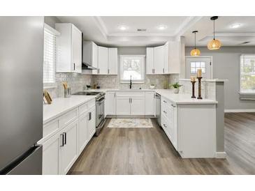 Bright kitchen with white cabinets, stainless steel appliances, and a peninsula island at 1406 Kennesaw Nw Dr, Atlanta, GA 30318