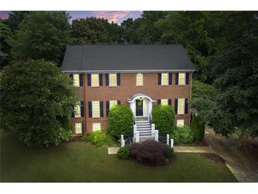 Charming brick two-story home featuring black shutters, manicured landscaping, and a welcoming front entrance at 10645 Tuxford Dr, Alpharetta, GA 30022