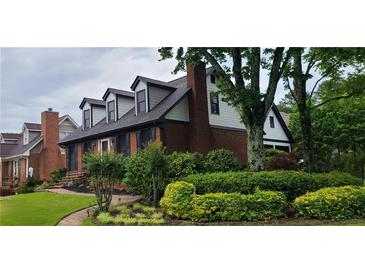 Charming brick home featuring dormer windows, lush landscaping, and a welcoming entrance at 2747 Livsey Trl, Tucker, GA 30084