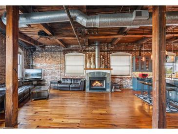 Open-concept living room with exposed brick, hardwood floors, fireplace, and industrial-style ceiling at 490 Marietta St Nw # 307, Atlanta, GA 30313