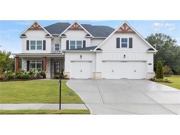 Beautiful home featuring a three-car garage, lush lawn, and charming stonework at 3330 Carswell Bnd, Cumming, GA 30028